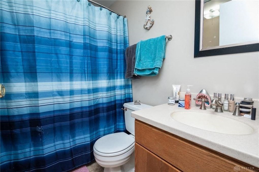 A blue plaid shower curtain hangs over a white toilet in a bathroom.