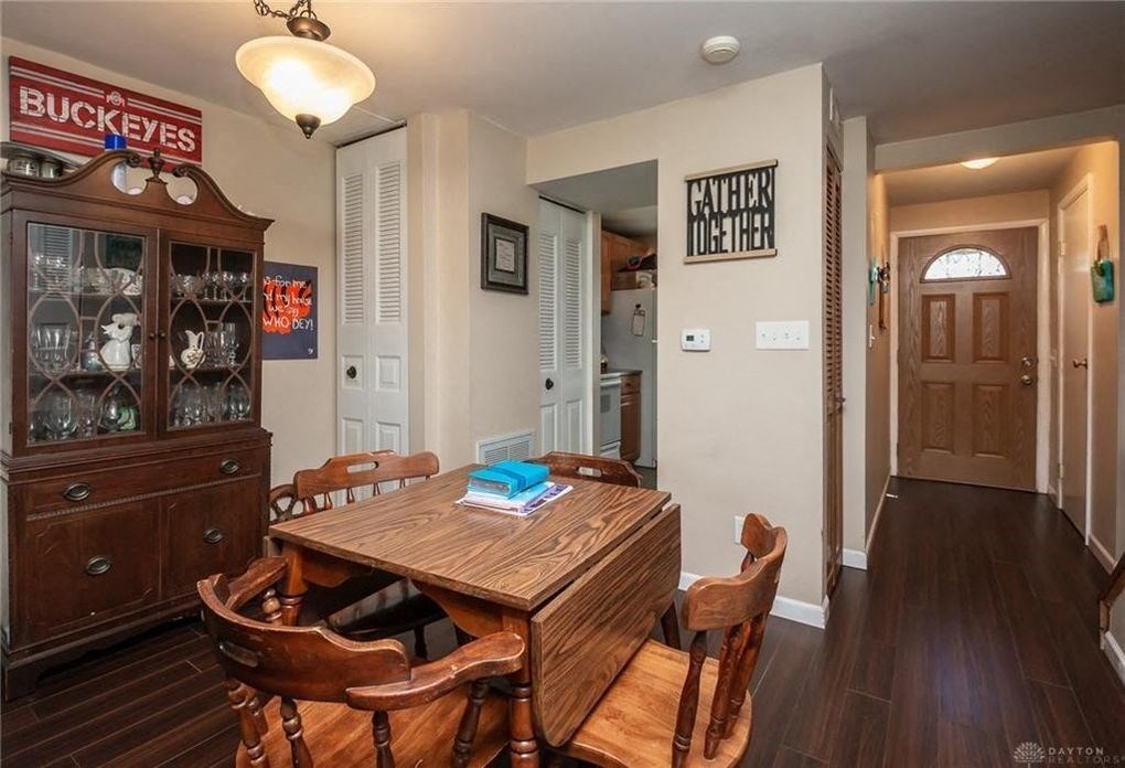 A wooden dining table with chairs and a cabinet with glass doors.