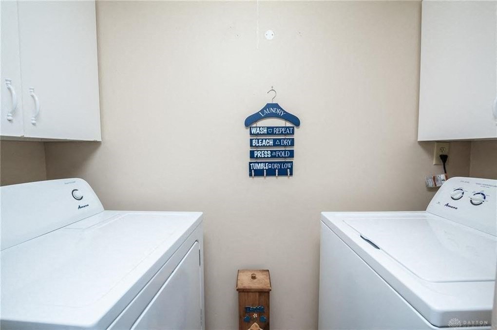 A laundry room with a sign that says "Wash Repeat" and two washing machines.
