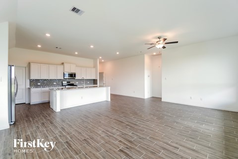 A spacious kitchen with a refrigerator, microwave, and a countertop with a sink.