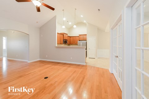 A spacious room with wooden floors and a ceiling fan.