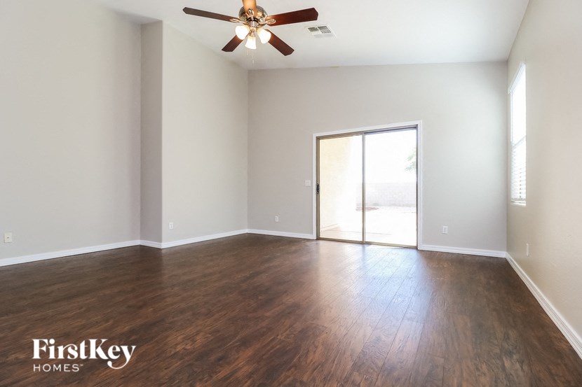 an empty living room with wood floors and a ceiling fan