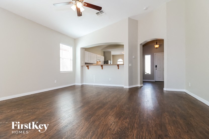 an empty living room with hardwood flooring and a ceiling fan