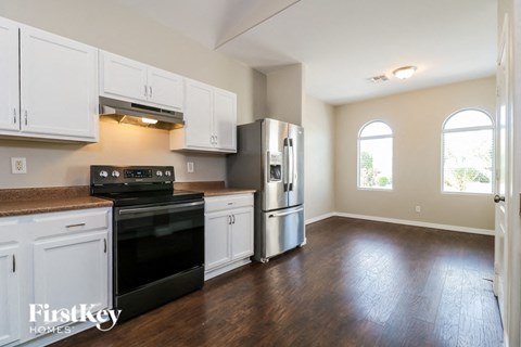 an empty kitchen with white cabinets and a black stove and refrigerator