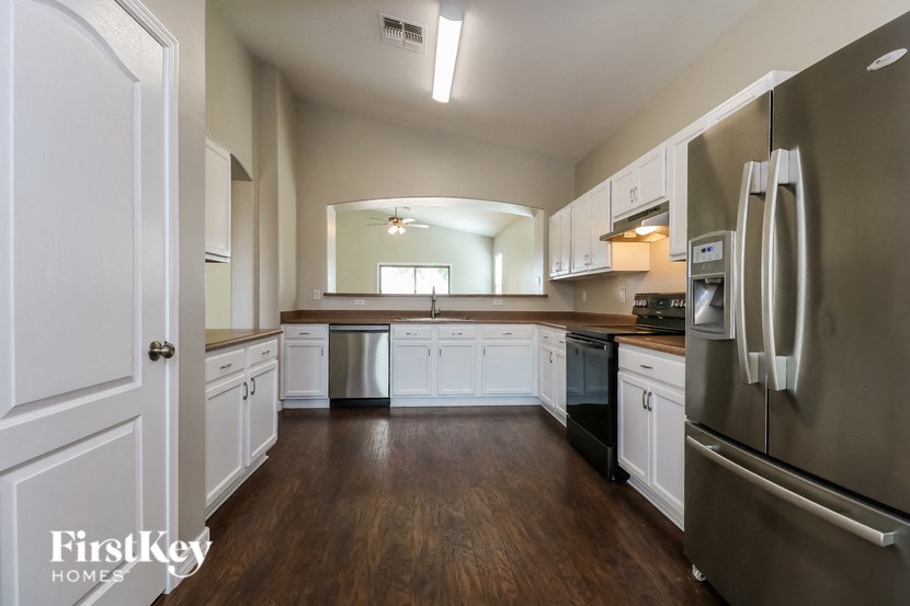an empty kitchen with white cabinets and stainless steel appliances
