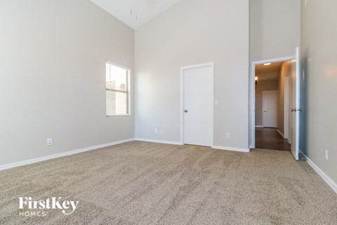 a spacious living room with carpet and a hallway to a bedroom