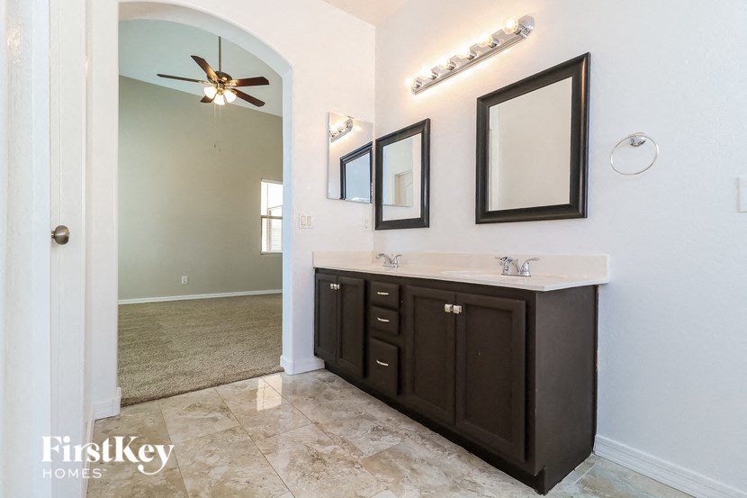 the master bathroom has a large vanity with two sinks and a large mirror
