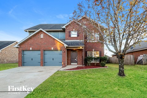 a brick house with blue garage doors and a tree