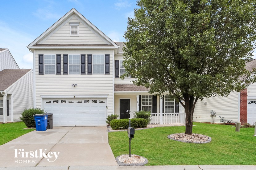 A white house with a tree in front of it.