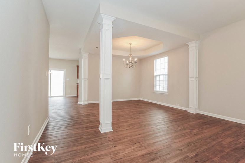 A large empty room with wooden floors and white columns.