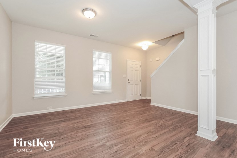 A room with wooden flooring and a staircase on the right side.