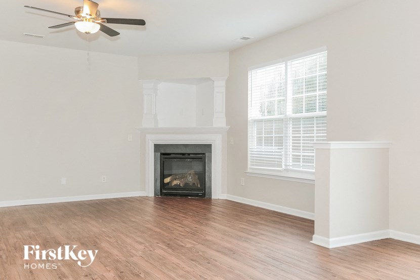 A living room with a fireplace and a ceiling fan.
