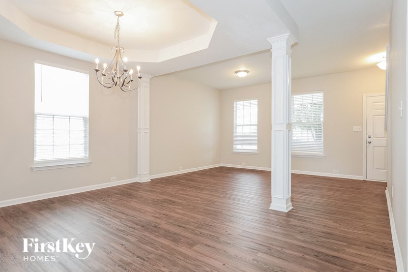 A large empty room with wooden floors and a chandelier.