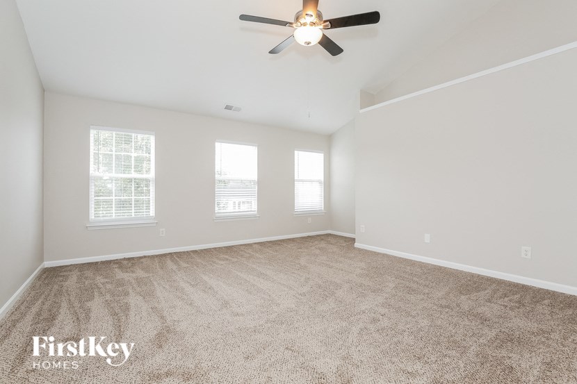 A spacious room with a carpeted floor and a ceiling fan.