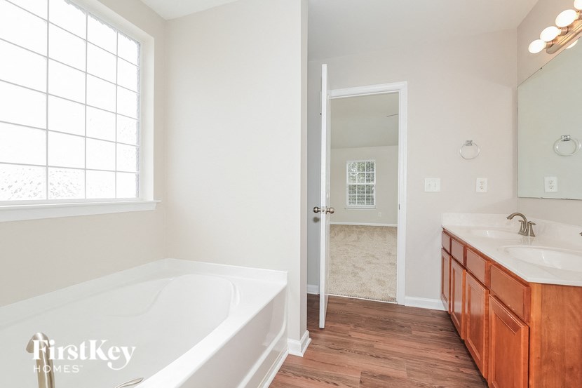 A white bathroom with a tub, sink and mirror.