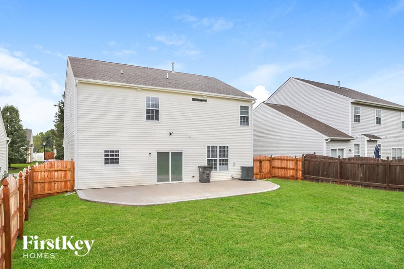 A white house with a brown fence and a green lawn.