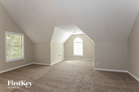 the living room of an attic with carpet and a window