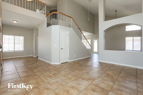 A spacious living room with a staircase and a large window.