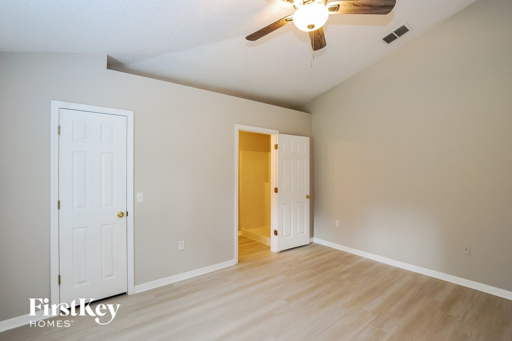 the living room of an empty house with a ceiling fan and a door to an