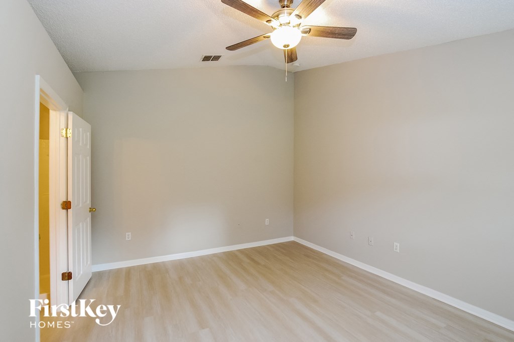 the living room of an empty house with wooden floors and a ceiling fan