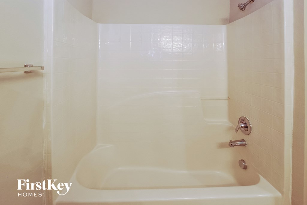 a white bath tub in a white tiled bathroom