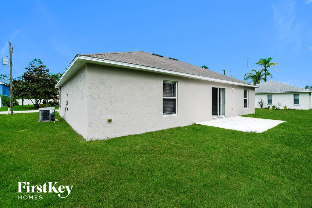 a small white house in a grassy yard with a blue sky