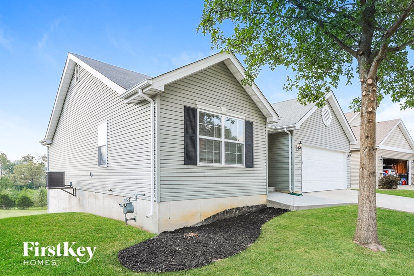 the exterior of a house with a yard and a tree