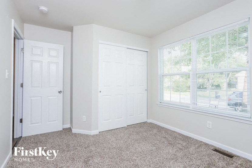 an empty bedroom with two doors and a window