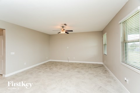 A spacious room with a ceiling fan and a window with blinds.