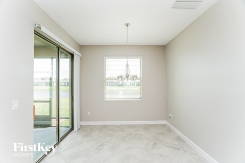 A room with a sliding glass door and a window with a chandelier hanging from the ceiling.