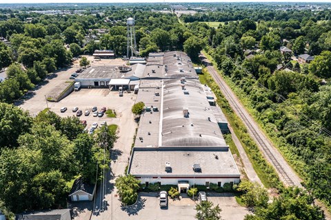 an aerial view of a large industrial building surrounded by trees and a railroad