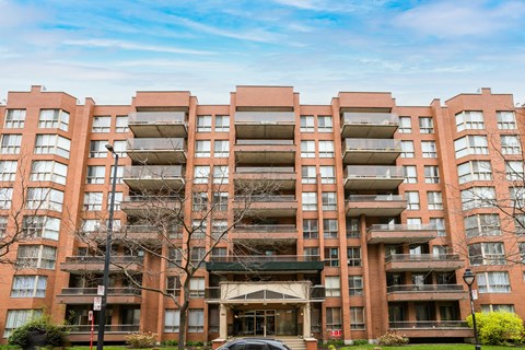 A large apartment building with a car parked in front.