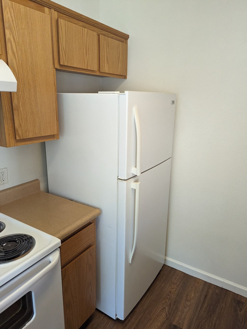 a kitchen with a refrigerator and stove and wooden cabinets
