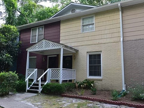 a yellow house with a white porch and a red
