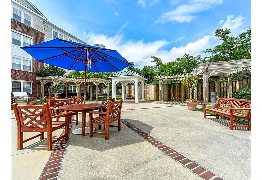a patio with tables and chairs and a blue umbrella
