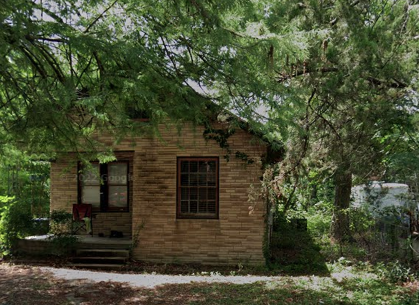a small brick house with trees in front of it