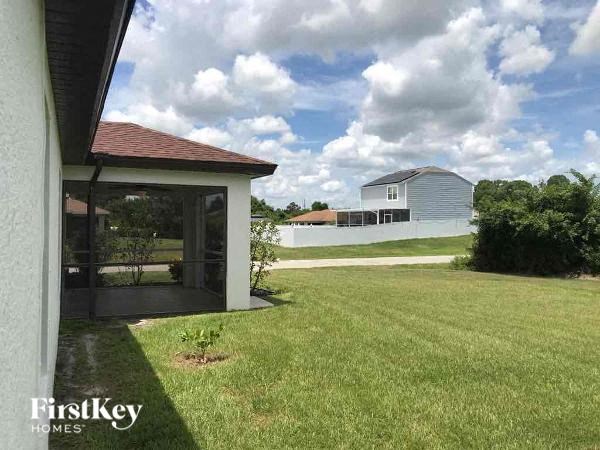 a backyard with a white house and a grass field