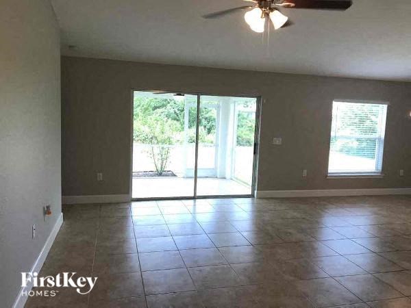 an empty living room with a ceiling fan and a sliding glass door