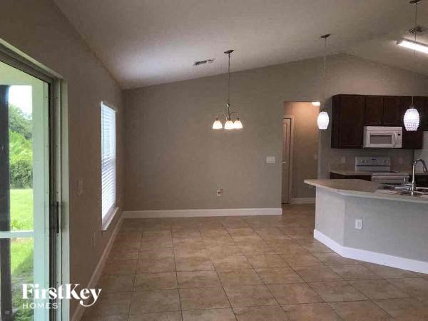an empty living room with a kitchen and a door