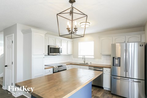 A kitchen with a wooden counter top and stainless steel appliances.
