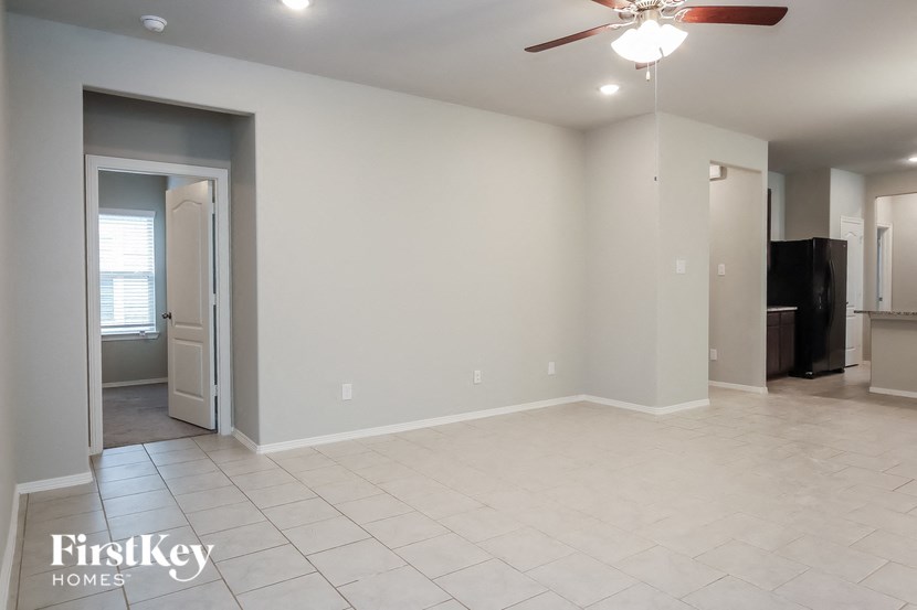 A spacious room with a ceiling fan and a door leading to another room.