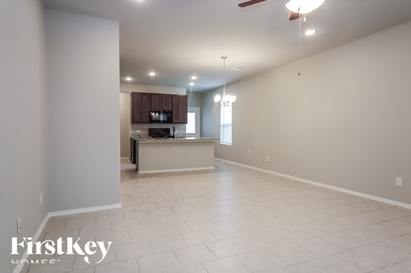 A spacious room with a kitchen area in the background.