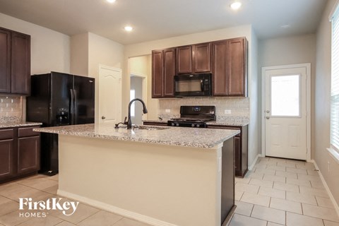 A kitchen with brown cabinets and a granite countertop.