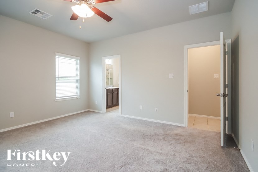 A spacious room with a ceiling fan and a door leading to another room.