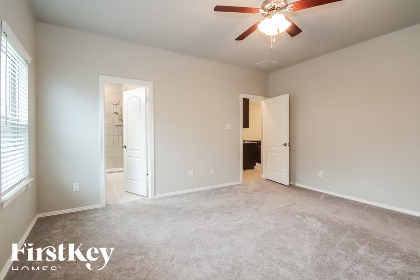 A spacious room with a ceiling fan and two doors.