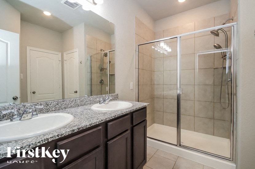 A bathroom with a sink, mirror, and shower.