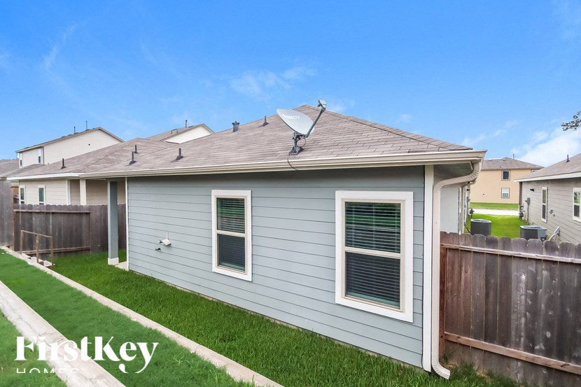 A house with a grey siding and a white window is shown.