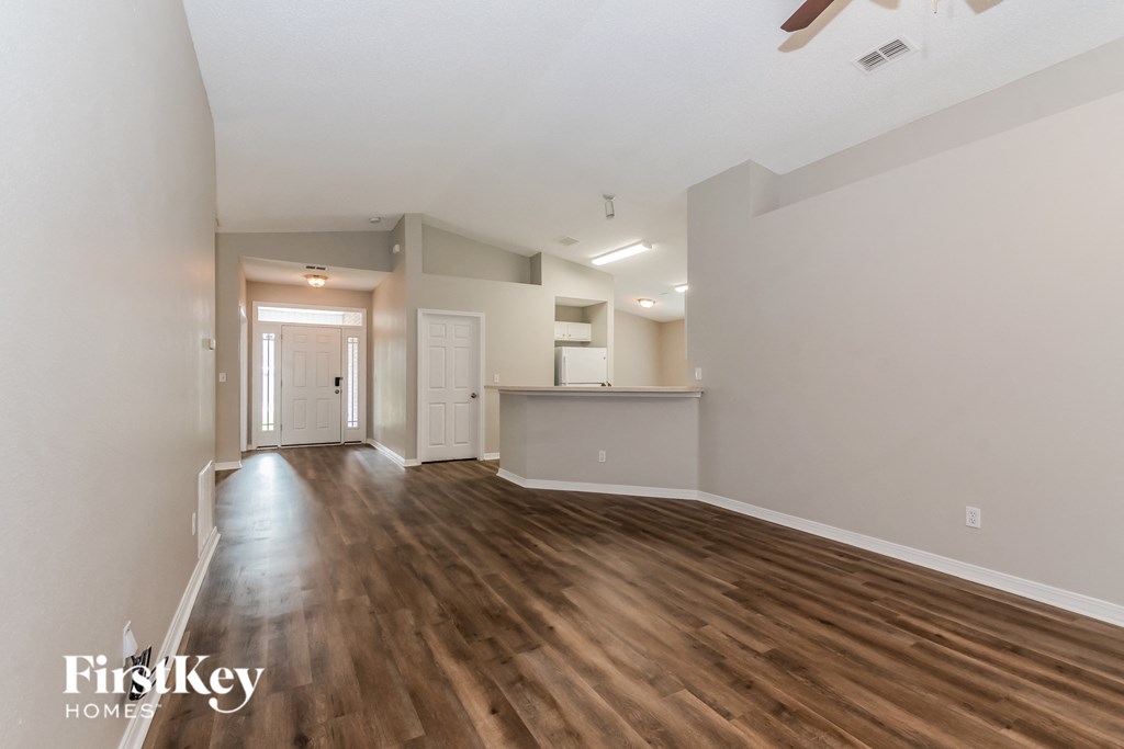 the living room and kitchen of an empty house with wood flooring