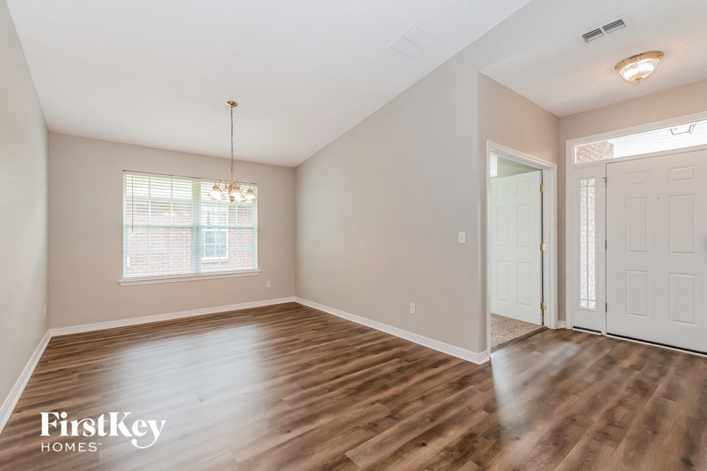 the spacious living room with hardwood flooring and a white door