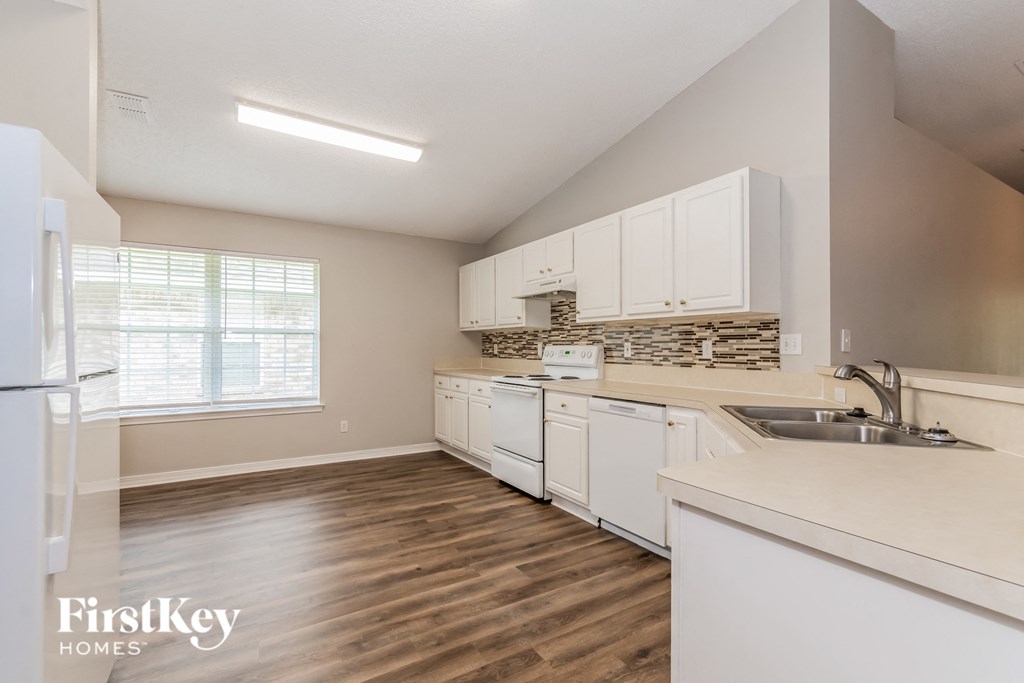 a kitchen with white cabinets and a sink and a refrigerator
